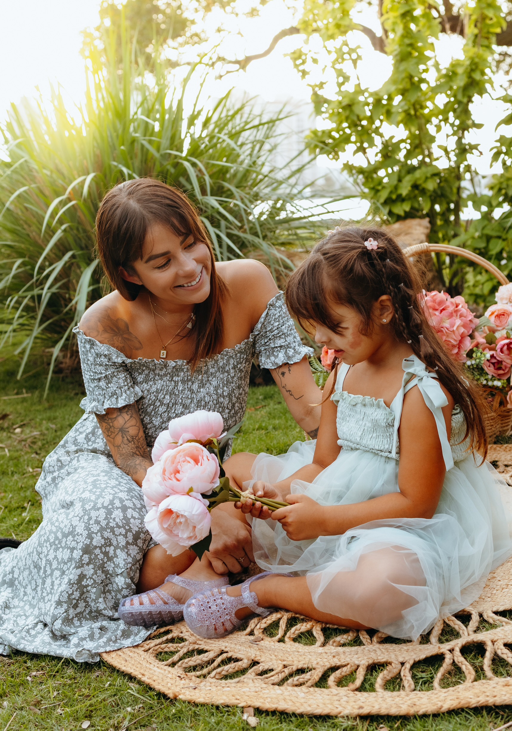 Woman and girl with flowers on picnic blanket