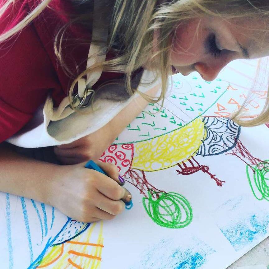 Child drawing colorful crayon artwork on paper